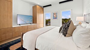 Un dormitorio moderno con una cama grande, un televisor en un mueble empotrado y vistas al exterior a través de una ventana.