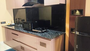 A kitchen with a microwave, stove, and refrigerator. - Cityscape, Siddha Xanadu, Newtown: Gym, pool, restaurant, garden, 24/7 security. (Kolkata)