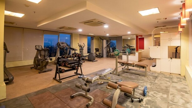 A gym with various exercise equipment, large windows, and a view of the city.