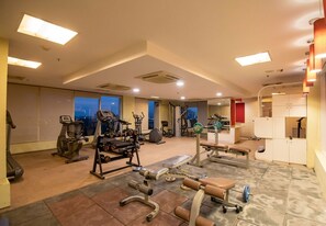 Een sportschool met diverse fitnessapparatuur, grote ramen en stadszicht.