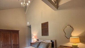 Et soveværelse med en seng, et træskab, et natbord med en lampe og en stol.