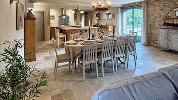 Un coin repas avec une table ronde dressée pour six personnes, entourée de chaises blanches.