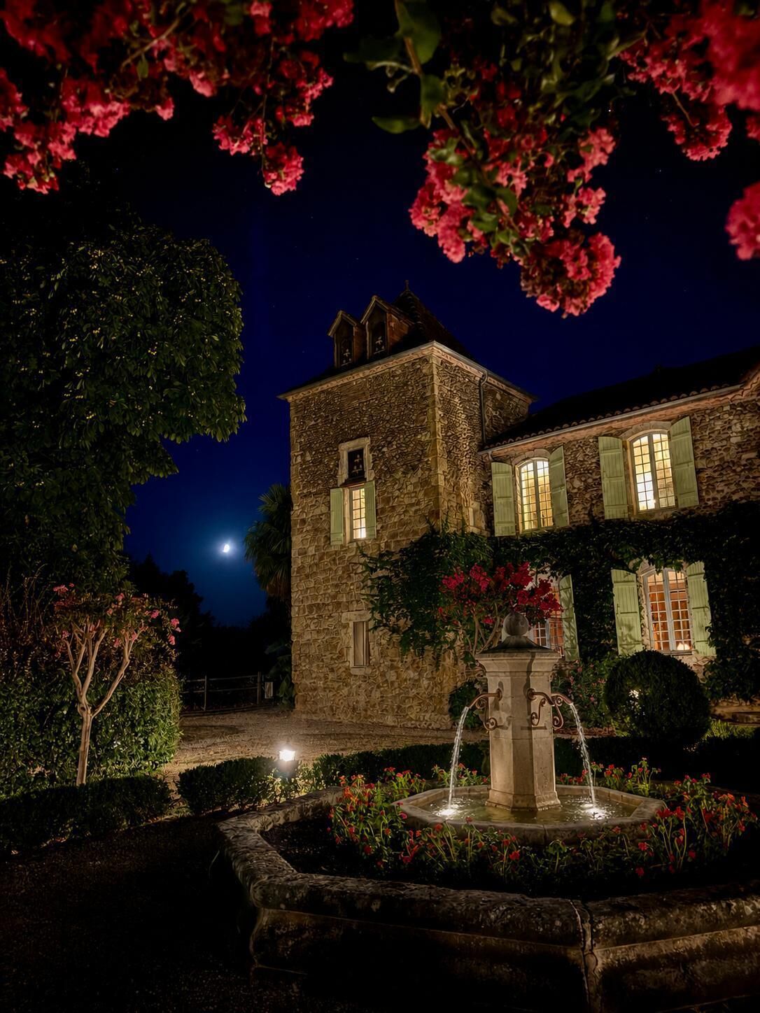 Un edificio de piedra con una fuente y una luna en el cielo.