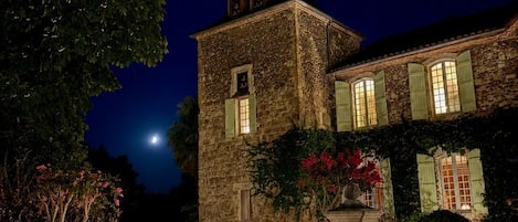 Un edificio de piedra con una fuente y una luna en el cielo.