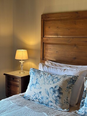 A bedroom with a wooden headboard, a nightstand with a lamp, and floral-patterned bedding. - Luxury chateau retreat; pool, summer kitchen, outdoor cinema & Madiran vineyards (Castelnau-Rivière-Basse)