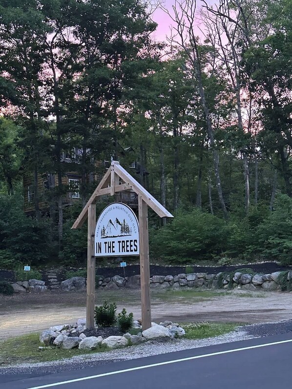 A wooden sign with a mountain and trees graphic, indicating a mountain resort or lodge. - White Mountains A-Frame | Off-Grid, Stars, Firepit (Stoneham)