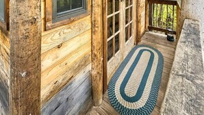 Una cabaña de troncos con un porche, una ventana y una puerta.