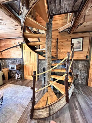 Un escalier en colimaçon avec des marches en bois et des rampes en corde, des murs en bois et une décoration intérieure de style rustique.