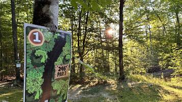 Wegweiser mit Karte und Entfernungshinweisen in einem bewaldeten Gebiet.