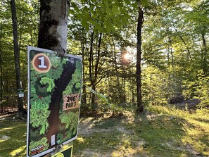 A trail sign with a map and distance markers in a wooded area.