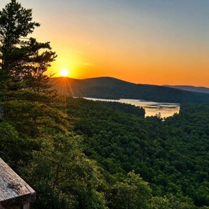 Un paysage boisé avec un plan d’eau et un coucher de soleil.