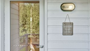 A white door with a glass panel, a mailbox, and a 'Welcome to our home' sign.
