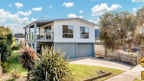 A modern two-story house with a balcony, a garage, and a well-maintained garden.
