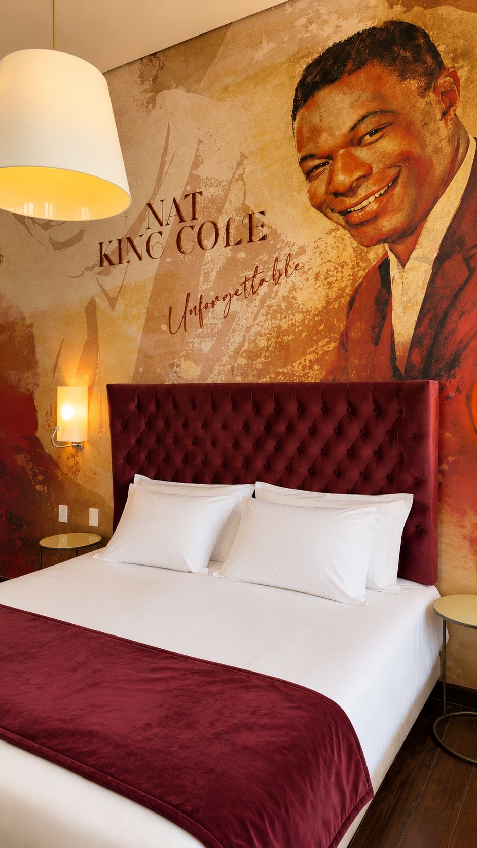 A hotel room with a large bed, a red upholstered headboard, and a wall mural featuring a portrait and text.