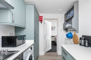 A compact kitchen with a microwave, washing machine, and a coffee maker. - Character filled 4 bed apartment in foody hotspot. (Redland)