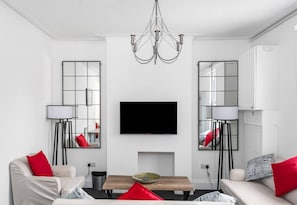 A modern living room with a flat-screen TV, a chandelier, and two floor lamps. - Character filled 4 bed apartment in foody hotspot. (Redland)