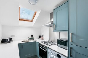 A compact kitchen with a skylight, a gas stove, a microwave, and a washing machine. - Character filled 4 bed apartment in foody hotspot. (Redland)