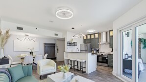 Un espace de vie moderne à aire ouverte comprenant une cuisine, un coin repas et une grande porte-fenêtre coulissante donnant sur un balcon.