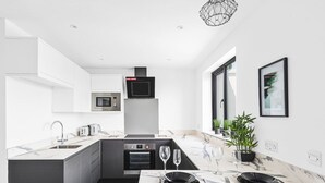Een moderne keuken met een centraal eiland, inbouwapparatuur en een eethoek voor vier personen.