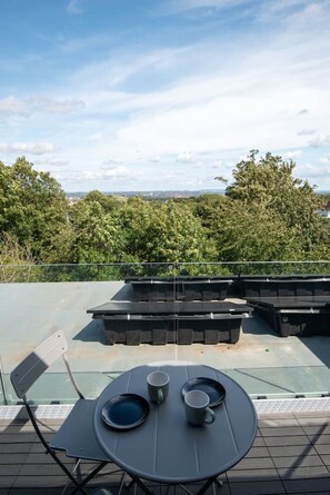 A rooftop terrace with a table set for two, surrounded by outdoor furniture. - Horizon View by MyCityHaven (Redland)