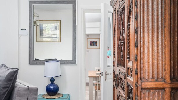 Une pièce comprenant un canapé, une lampe, un miroir et un meuble en bois.