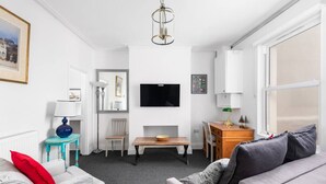Un salon moderne avec un canapé, une table, un téléviseur et une lampe.