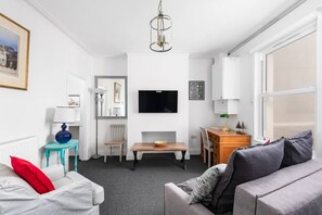 Ein modernes Wohnzimmer mit einer Couch, einem Tisch, einem Fernseher und einer Lampe.