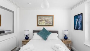 Une chambre d’hôtel avec un grand lit, deux tables de chevet avec des lampes, une carte encadrée accrochée au mur et un tableau.