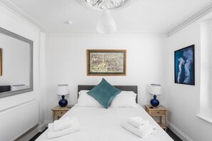 Ein Hotelzimmer mit einem großen Bett, zwei Nachttischen mit Lampen, einer gerahmten Karte an der Wand und einem Gemälde.