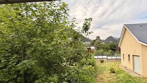 Et boligområde med et hus, en indhegnet have og et bjerg i baggrunden.