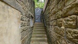 Un escalier étroit en pierre menant à une porte surmontée d’un portail en métal.