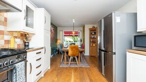 Uma cozinha moderna com fogão, forno, geladeira e micro-ondas. Há uma área de jantar com mesa e cadeiras.