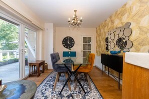 A dining area with a glass table, two chairs, a chandelier, and a wall clock. - Large family home on the outskirts of Bath - Pass the Keys (Bath)