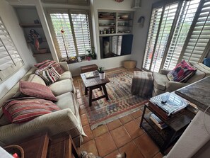 A cozy living room with a sofa, armchair, coffee table, and a bookshelf. - Ventana Canyon Golf and Racquet Club 2-bedroom townhome (Tucson)