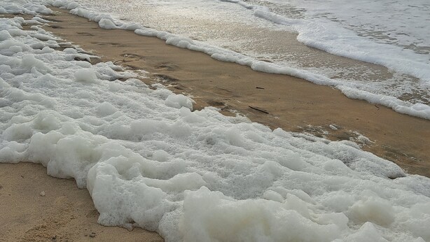 Een strand met golven en een bewolkte lucht.