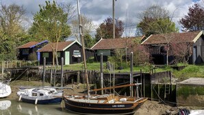 Een rustiek waterlandschap met aangemeerde boten, houten huizen en een heldere lucht.