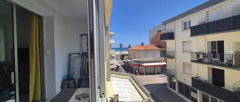 Una calle estrecha flanqueada por edificios, cielo azul despejado y una vista al mar en la distancia.