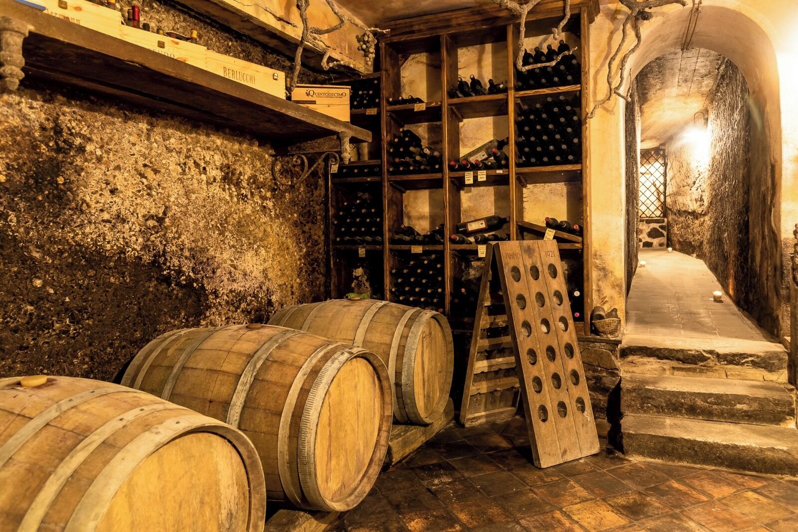 Ein Keller mit Holzfässern, Weinschränken und einer Steinwand.