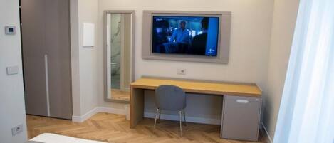 A bedroom with a bed, a desk, a chair, a television, and a wardrobe.
