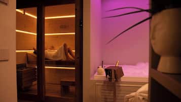Um quarto de spa com chão de madeira, uma mesa de massagem, uma cadeira de massagem e uma garrafa de champanhe.