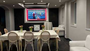 A modern living room with a dining area, a flat-screen TV, and a white sofa.