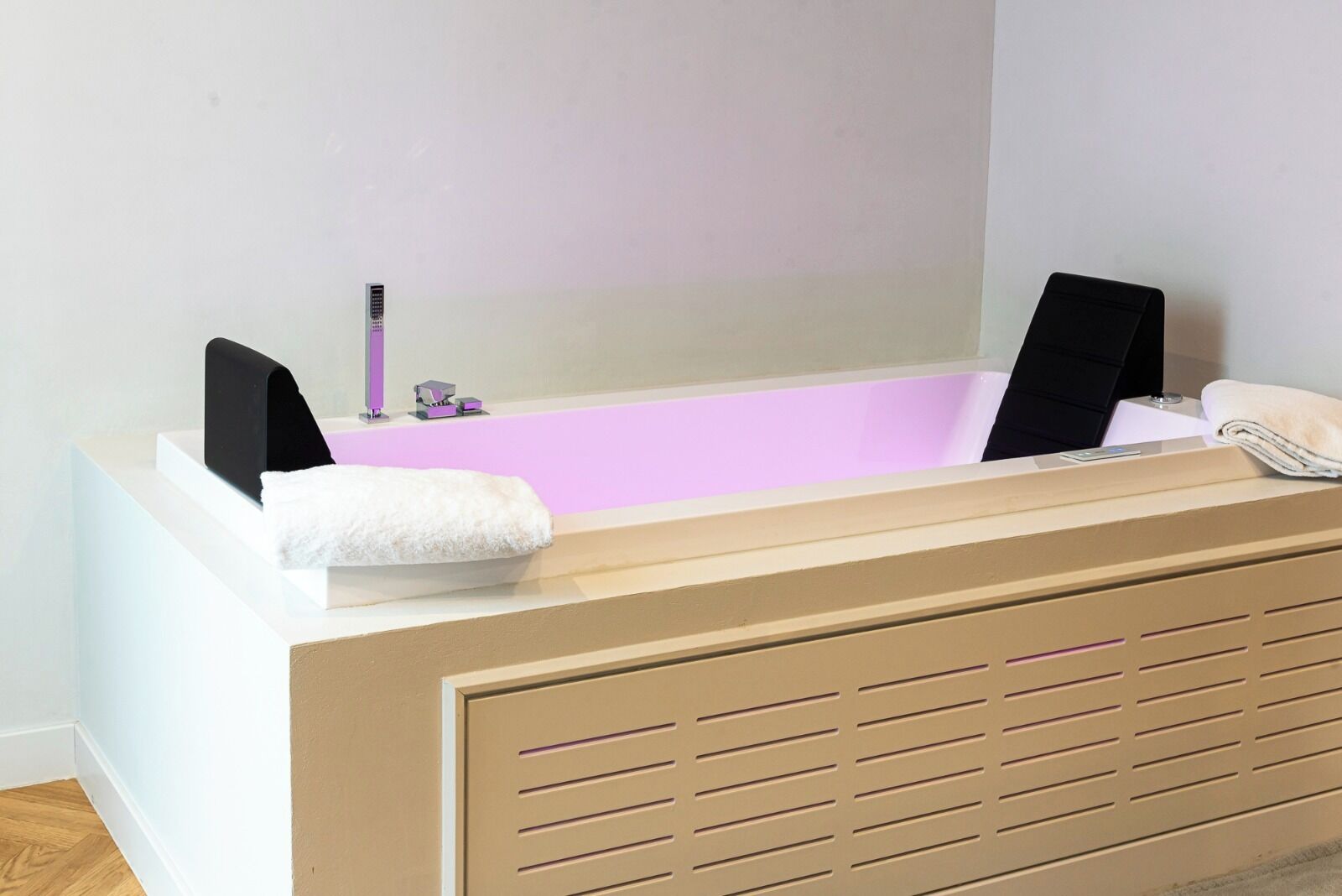Un baño moderno con bañera, una toalla y un lavamanos pequeño.