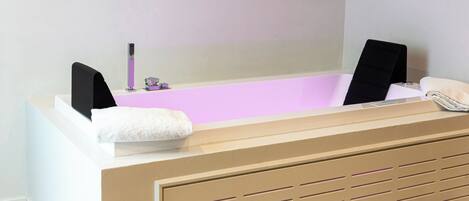 A modern bathroom with a bathtub, a towel, and a small sink.