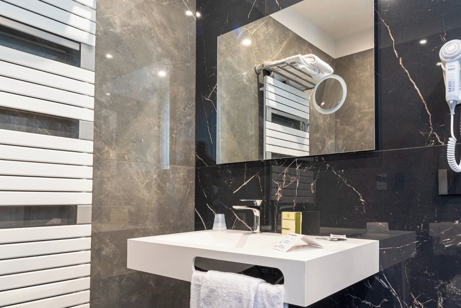 Une salle de bain moderne avec un meuble-lavabo blanc, un sèche-cheveux et un porte-serviettes.