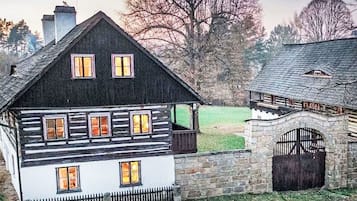 Una tradizionale baita di legno con un ingresso in pietra e diverse finestre.