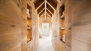Un couloir intérieur aux murs en bois, doté d’étagères intégrées et d’un sol carrelé.