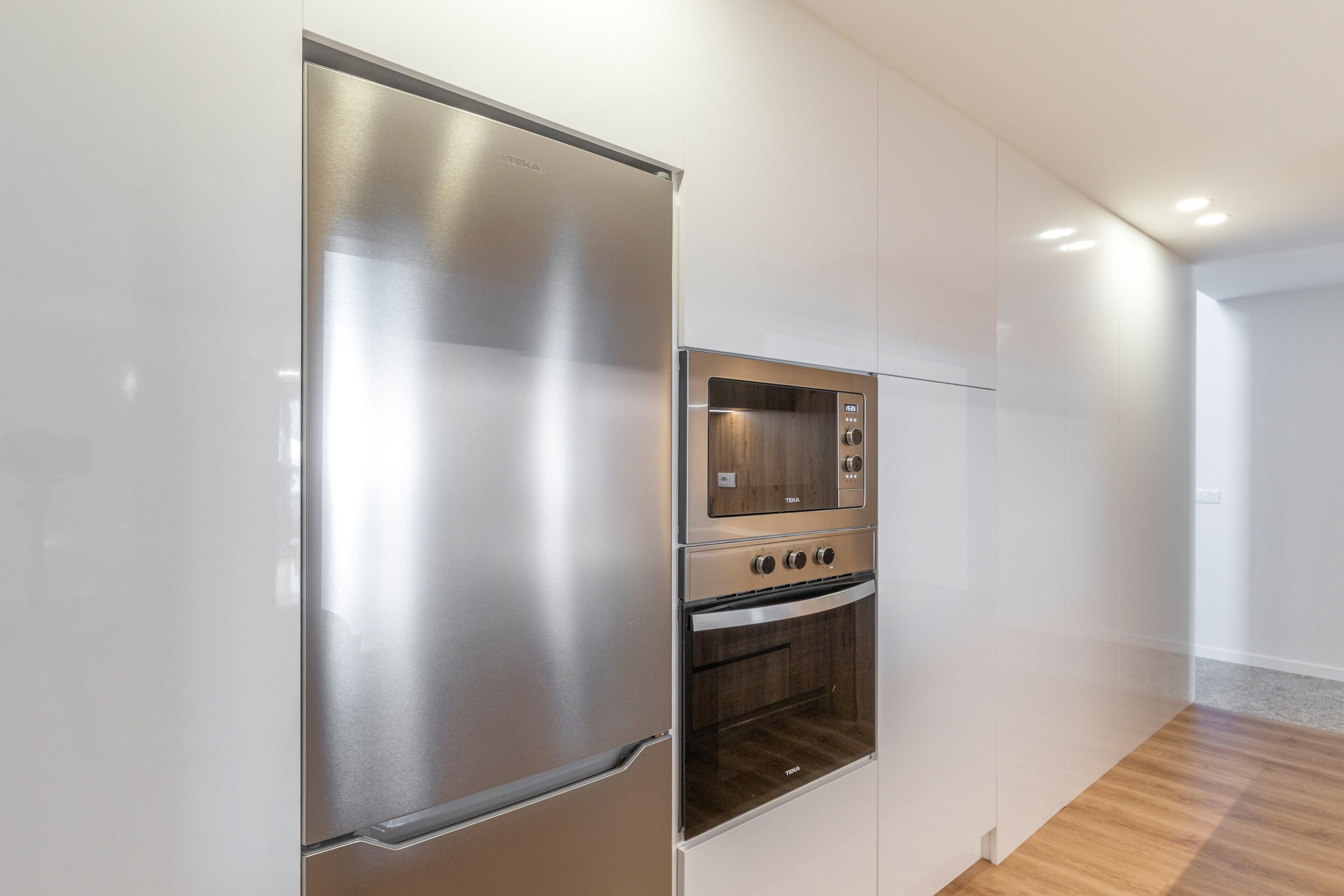A modern kitchen with stainless steel appliances, including a refrigerator and oven, and white cabinetry.