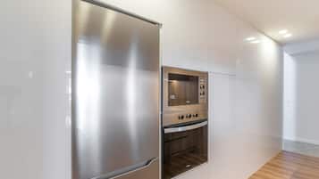 A modern kitchen with stainless steel appliances, including a refrigerator and oven, and white cabinetry.