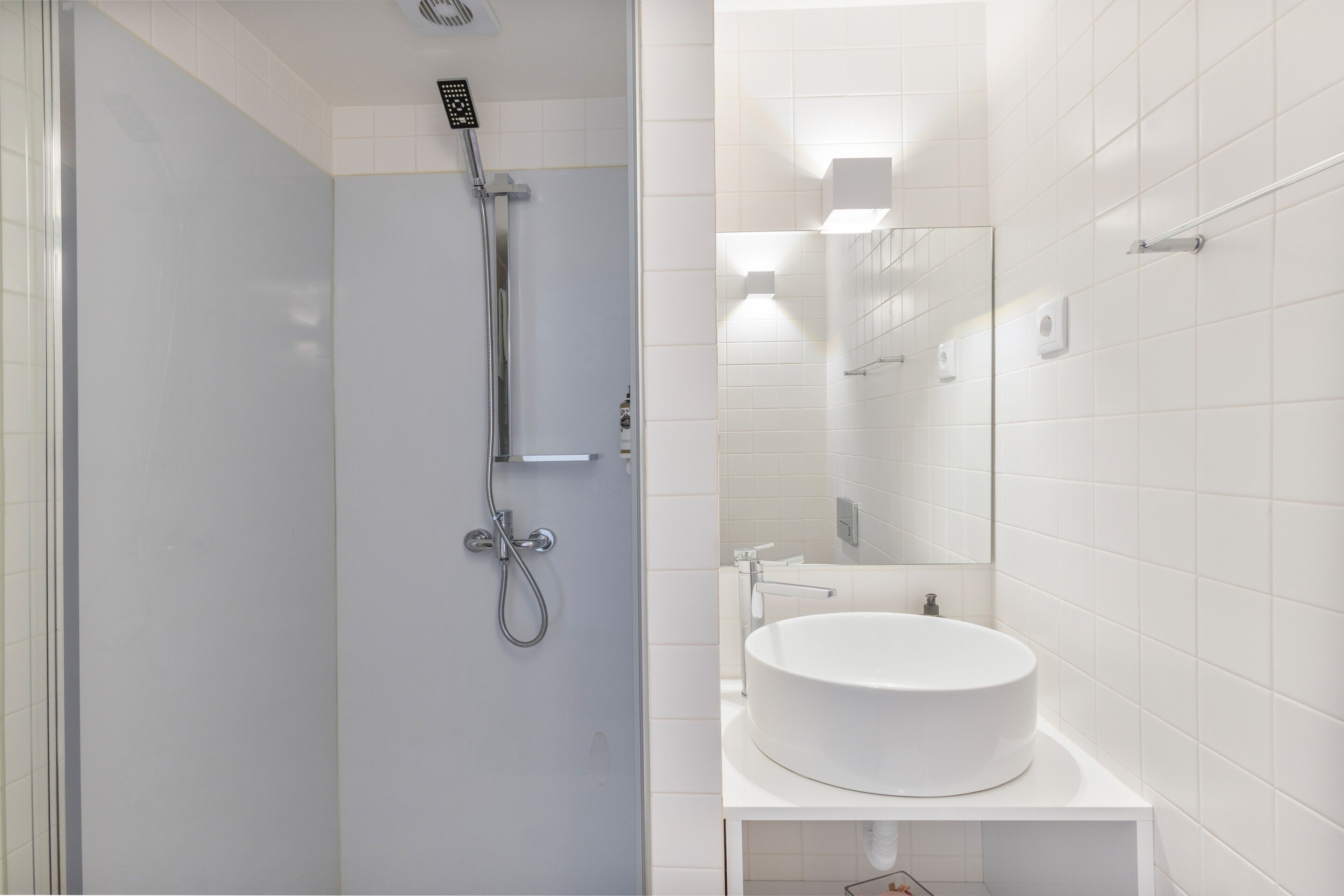 Une salle de bain moderne avec une douche à parois de verre, un lavabo blanc et un miroir.