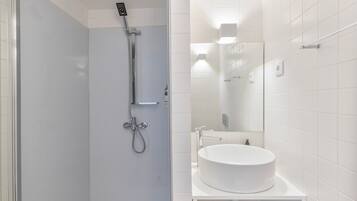 Une salle de bain moderne avec une douche à parois de verre, un lavabo blanc et un miroir.